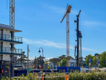 A construction site of an apartment building on the Baltic Sea in Mrzezyno, Poland with a crane and a machine for drilling holes in the ground (a huge drill).の写真素材