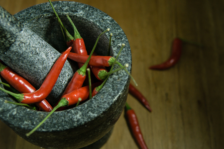 red chili is in the mortar stone on the wooden tableの写真素材