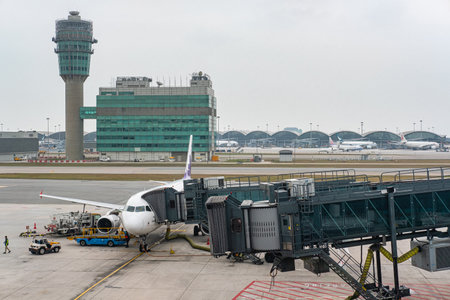 HONG KONG, CHINA - JANUARY 14, 2019: Airplane with Loading Dock at Hong Kong International Airport. Control tower in the background. Ground operation of Commercial Air Transport.のeditorial素材