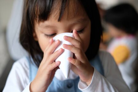Cute Asian kid, Child, little girl drinking water from white paper cone cup.の写真素材