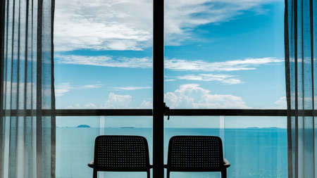 Back view from the window of 2 chairs on the balcony, sea and sky views.の写真素材
