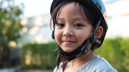 Smiling cute Asian kid wearing safety helmet in the park. Sport outdoor activity for kid.の写真素材