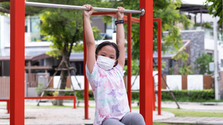 Little girl wearing a mask playing at playground, during the coronavirus outbreak.の写真素材