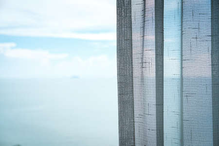 Close up, curtains in the hotel room, blurred sea and  sky background.