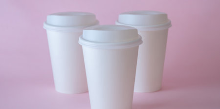 Three white paper coffee cups on pink background, coffee cup mock up.の写真素材