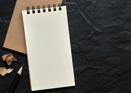 Open Blank Spiral Notebook with Black Pencil and Pencil Shavings on Black Background, Copy Space for...