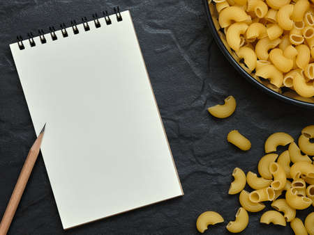 Open Empty Notebook and Pencil with Macaroni Pasta on Black Background, Copy Space for Text, Food...