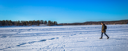 Falun - March 31, 2018: Traveler hiking on the frozen lake at Framby Udde near the town of Falun in Dalarna, Swedenのeditorial素材