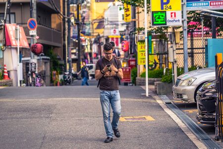 Osaka - June 01, 2019: Portrait of a male western traveler using his phone in Osaka, Japanのeditorial素材