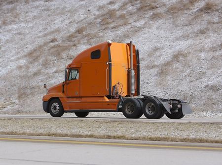 Orange Semi Truck on Highway without Trailerの写真素材