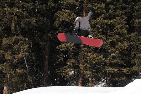 Gliding through the air on a snowboard while doing a trick off a jump.の写真素材