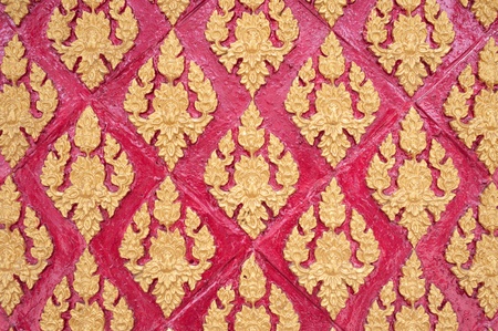Thai stucco pattern style on wall with golden painted colorの写真素材
