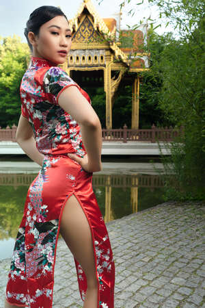 Young asian woman poses in front of a pagodaの写真素材