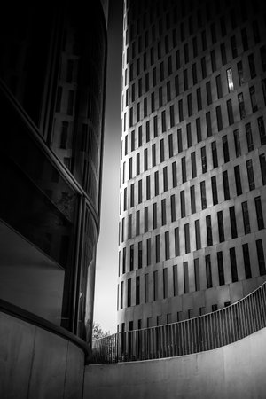 Black and white photo of a modern office building that shows that sun almost cannot fight the darkness of modern architecture anymore.の写真素材