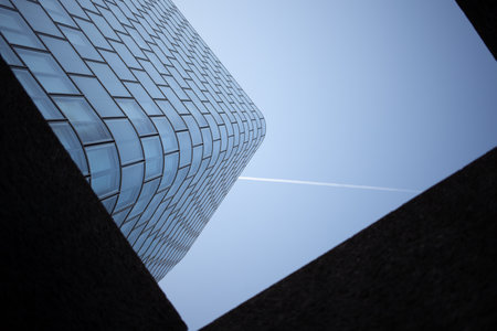 almost framed glass wall of a modern building showing modern time with a trace of modern travel as you see a chemtrail tooの写真素材