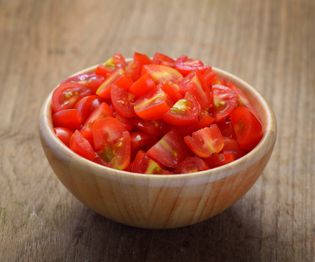 Cherry tomato sliced in wooden bowlの写真素材