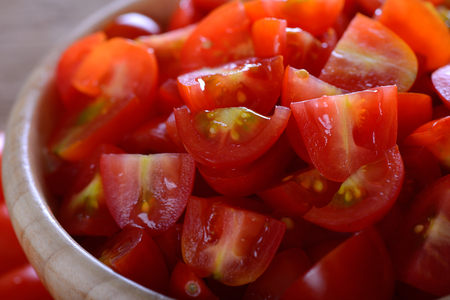 Cherry tomato sliced in wooden bowlの写真素材