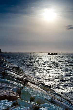 Stone beach and ocean under sun in a blue sky