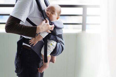 A mother and her five-month-old baby on a walk by baby carrierの写真素材