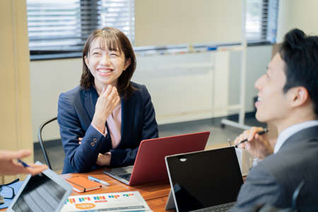Two male and female businessmen having a meeting on a laptopの写真素材