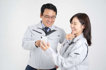 Male and female businessmen in work clothes having a meeting on a smartphone White backgroundの写真素材