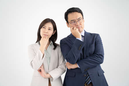 Male and female businessmen in thinking poses white backgroundの写真素材