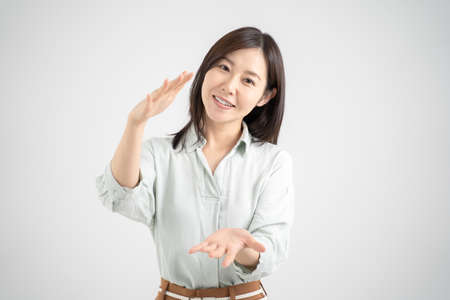 Female explaining service with a smile, white studio shot backgroundの写真素材