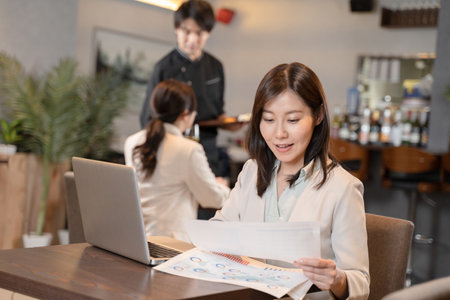 Female doing remote work at a restaurantの写真素材