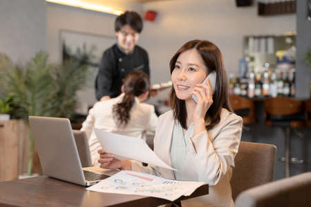 Female doing remote work at a restaurantの写真素材
