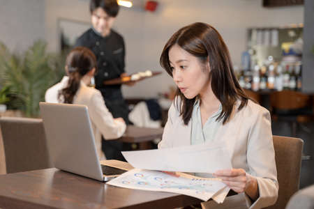 Female doing remote work at a restaurantの写真素材
