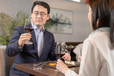Men and women toasting with wine at a restaurantの写真素材