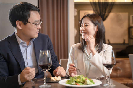 Men and women eating while having a conversation at a restaurantの写真素材