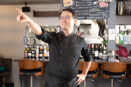 A man who runs a restaurant pointing to a pointの写真素材