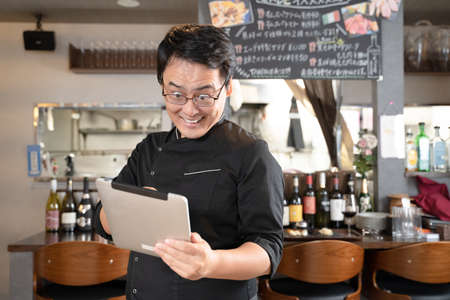 Male staff operating a tablet at a restaurantの写真素材