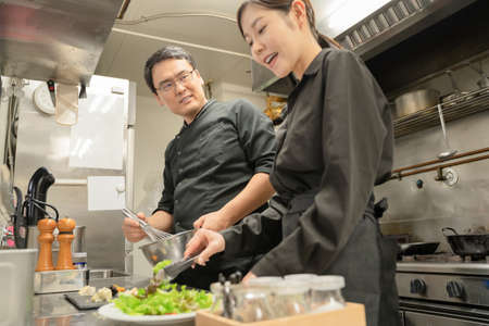 Male and female staff serving food at the restaurantの写真素材