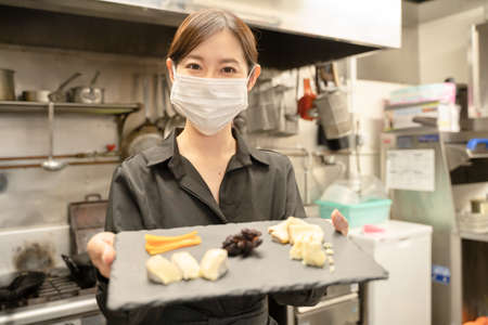 Female staff who wear masks to prevent infectious diseases and provide mealsの写真素材