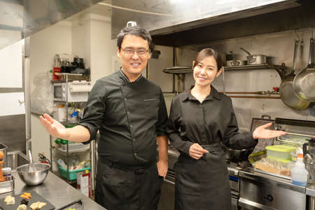 Male and female staff serving food at the restaurantの写真素材