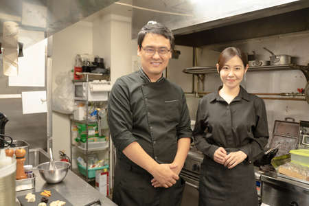 Male and female staff serving food at the restaurantの写真素材