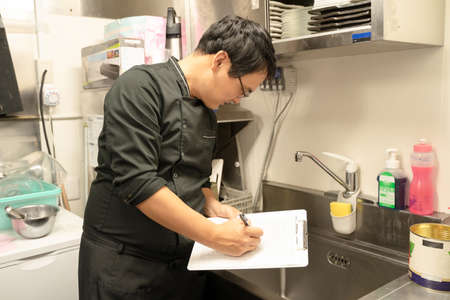 Male staff checking food hygiene managementの写真素材