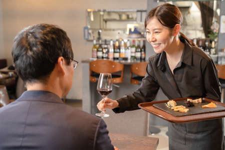 Female staff and male customers serving beerの写真素材