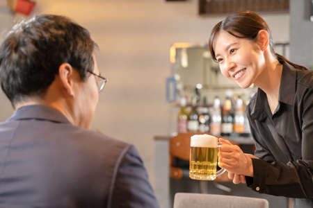 Female staff and male customers serving beerの写真素材