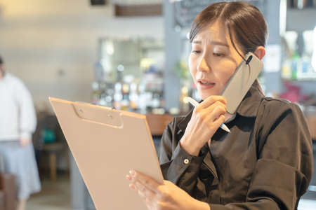 Busy female clerk to contact with smartphoneの写真素材