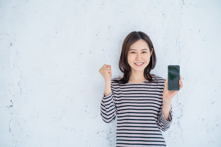 Young asian woman showing mobile phone with blank screen on white backgroundの写真素材