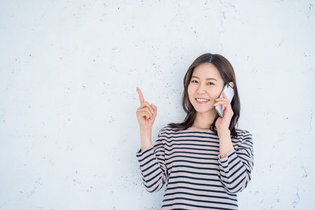 Portrait of a happy young asian woman talking on mobile phoneの写真素材
