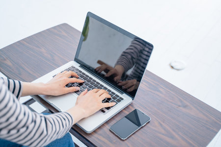 Woman using laptop with blank screen on wooden desk. View from aboveの写真素材