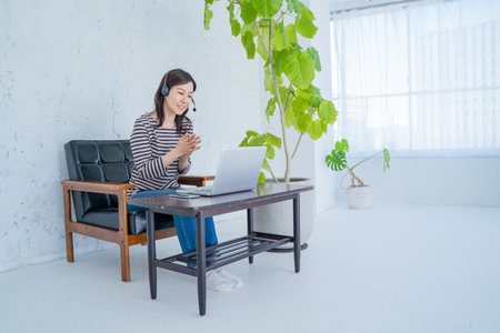 young asian woman working with laptop and listening to music at homeの写真素材
