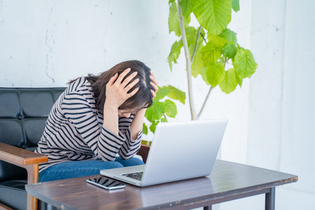 Upset young woman sitting at the table with laptop computer.の写真素材