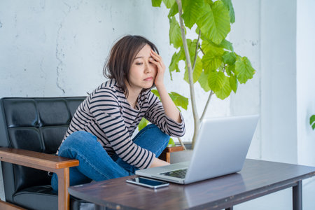 Young woman sitting at home with laptop computer and thinking about something.の写真素材