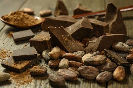 pieces of chocolate with cocoa beans lie on a wooden table