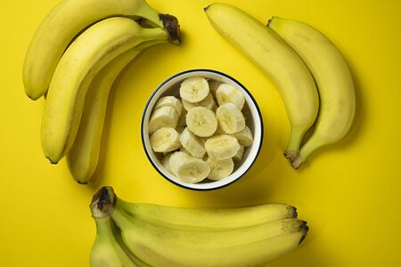 whole and sliced bananas on a yellow tableの写真素材